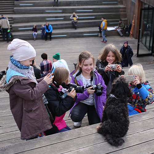  Zdjęcia przedstawia grupę dzieci robiących zdjęcie pieskowi w amfiteatrze SDK
