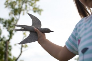 Na zdjęciu: na tle nieba dziecko z własnoręcznie uszytym ze skrawków tkanin ptakiem. Foto: Dominika Dzieniszewska