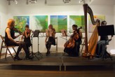 Na zdjęciu artyści podczas koncertu w dawnej siedzibie SDK. Na scenie pięć kobiet siedzących przy instrumentach smyczkowych oraz harfie. 
