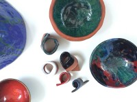 Zdjęcie przedstawia prace ceramiczne wykonane przez uczestników warsztatów oraz farby do kolorowania ceramiki.