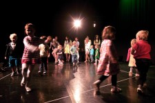 Na zdjęciu widoczna jest grupa małych dzieci bawiących się na scenie teatralnej.