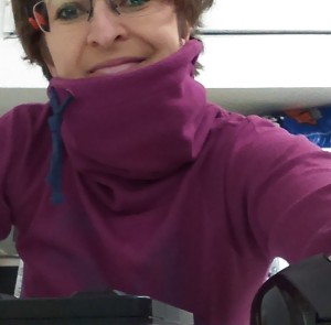 Na selfie widać kobietę w krótkich włosach i w okularach. Fioletowa bluza dominuje zdjęcie, zakrywając całe ciało i szyję.