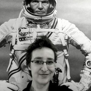 Na czarnobiałym selfie widać kobietę ustawioną tyłem do innego zdjęcia - kosmonauty w pełnym kombinezonie. Fotografowana jest widoczna tylko do szyi.