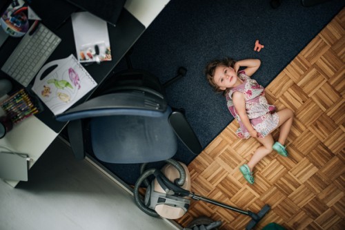 1.	Dziewczynka leżąca na podłodze, patrząca się wprost w obiektyw aparatu. Od lewej, w lewym górnym rogu stoi biurko, a na nim laptop. Przy biurku stoi krzesło i odkurzacz.