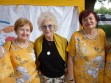 Występ na Południowo Praskich Senioraliach. Dwie wokalistki z zespołu Służewianki na zdjęciu z DJ Wiką. Służewianki ubrane w żółte bluzki.