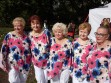 Występy w ogrodzie Saskim. Na zdjęciu 5 wokalistek zespołu Służewianki pozuje na tle pikniku. Ubrane w białe spodnie oraz kolorowe bluzki z wzorami kwiatów. 