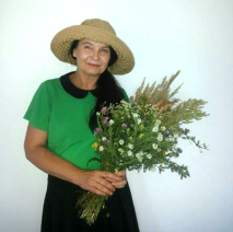 Na zdjęciu autorka wystawy w słomianym kapeluszu z bukietem polnych kwiatów. Foto: zasoby Doroty Nalewajk