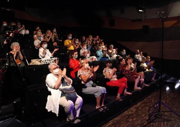 Na zdjęciu bijąca brawo widownia podczas koncertu Warszawskich Spotkań Muzycznych w SDK. Widzów jest około trzydziestu-czterdziestu i każdy z nich ma nałożoną maseczkę ochronną na twarz. Widzowie siedzą na czarnych fotelach w odstępach co drugie miejsce.