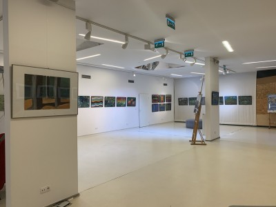 Zdjęcie przedstawia przestrzeń Galerii przy Kozach z wystawionymi pracami uczestników projektu "Onkoprzestrzeń kreatywna". Na białych ścianach wisi kilkanaście prac. W głębi zdjęcia widać dzienne światło oraz oświetlenie wystawiennicze.