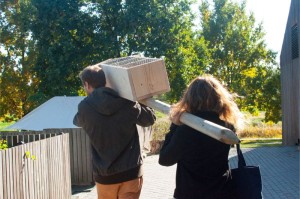 Zdjęcie przedstawia kobietę i mężczyznę od tyłu niosących domek dla zapylaczy do wspólnego ogrodu.