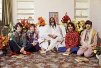 Na zdjęciu grupa oósb w pokoju siedząca na podłodze: w środku, ubrany w jasne szaty guru Maharishi Mahesh Yogi, po jego prawej stronie Paul McCartney i John Lennon; po lewej George Harrison i Ringo Starr.